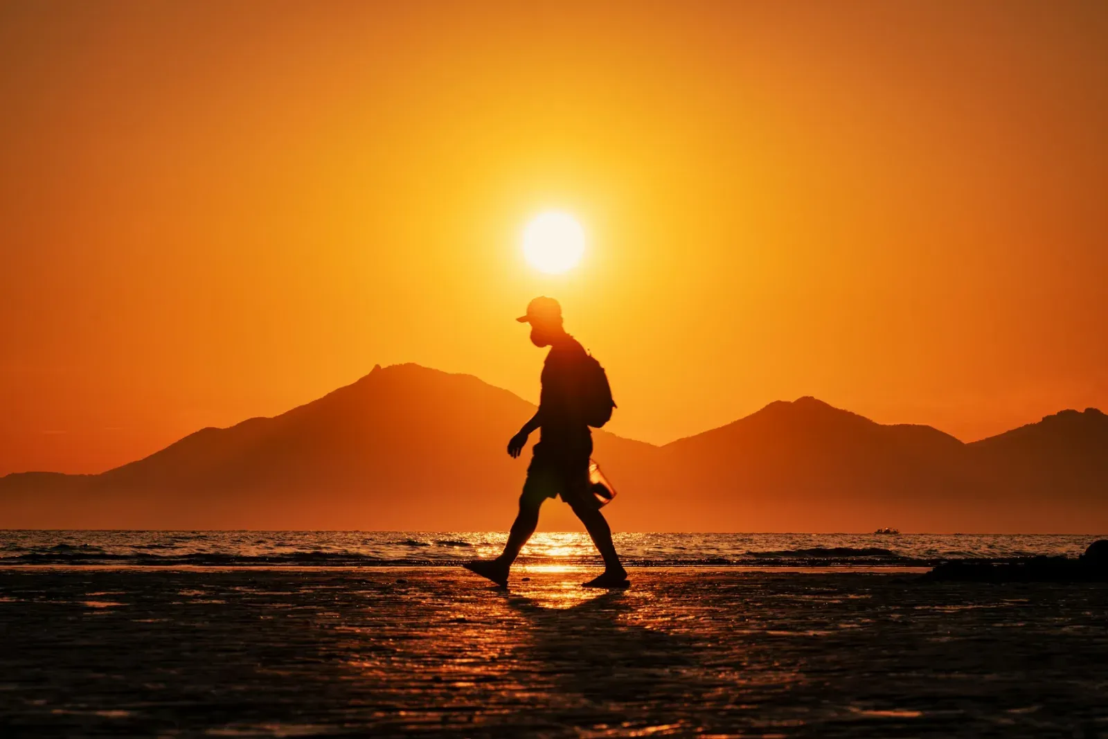 A person crossing Dadaepo Beach at sunset